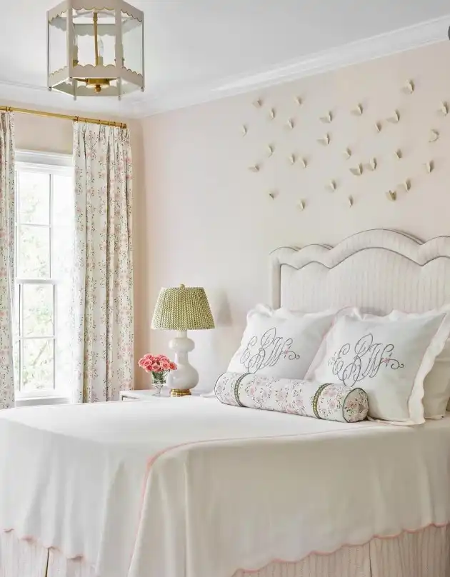 Vintage feminine bedroom ideas with pink walls, monogrammed pillows, and butterfly wall art